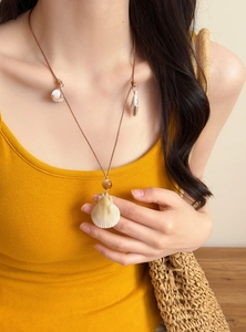 Close-up of beach vacation shell conch necklace with brown leather cord on model