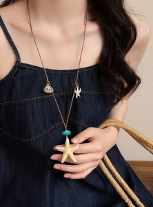 Close-up of a beach-style cord necklace featuring a large starfish and seashell pendant