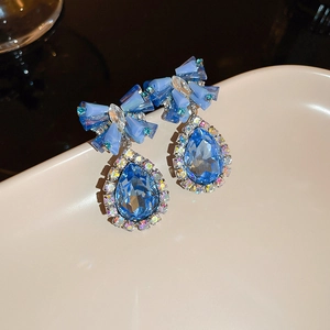 Close-up of elegant blue bow earrings with sparkling pear-shaped crystal drops