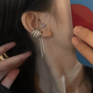Close-up of a stylish silver ear cuff with long metallic tassels on a model's ear
