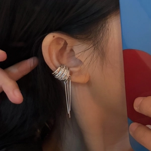 Close-up of a stylish silver wide-edge ear cuff with long metallic tassel pendants
