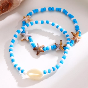Detalle de conjunto de tobilleras de cuentas azules y blancas con dijes de estrellas de mar