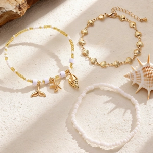 Detalle en primer plano de set de tobilleras marinas con dijes de estrella de mar y conchas.