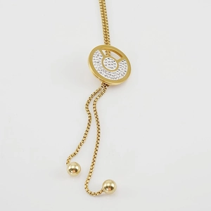 Primer plano de collar largo de acero inoxidable dorado con colgante circular de diamantes