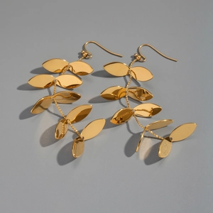 Close-up of golden leaf tassel earrings featuring a high-polish mirror finish and sleek design