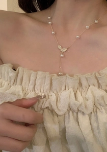 Detailed view of 18K gold plated necklace with pearls and zircon leaf pendant on model
