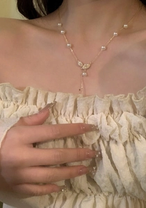 Close-up of elegant 18k gold plated leaf necklace with pearls and zircons on skin