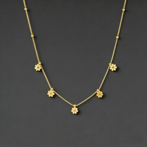 Close-up of golden daisy flower necklace featuring five small floral charms on a beaded chain