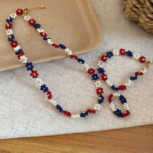 Close-up of handmade beaded flower necklace, bracelet, and ring set in red, white and blue