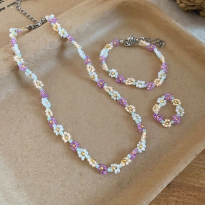 Detailed view of handmade beaded flower jewelry set with purple and white blossoms