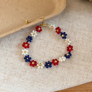 Detailed view of a handmade beaded flower bracelet with red, blue, and white flower patterns