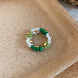 Macro view of a handmade Mori-style beaded flower ring with white and green beads