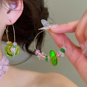 Detailed view of forest-style crystal beaded gold hoop earrings with green accents