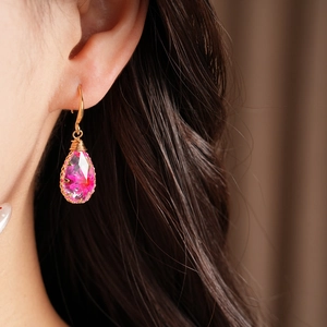 Macro detail of teardrop resin earrings with pink dried flowers on a model's ear
