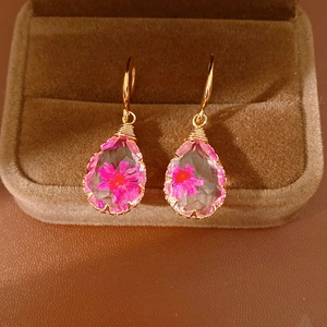 Close-up of teardrop resin earrings featuring real pink dried flowers inside
