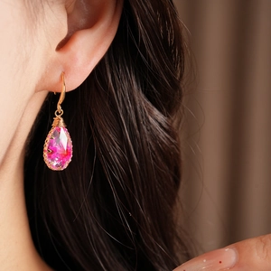 Detail shot of teardrop resin hook earrings featuring pink flowers on a gold hook.
