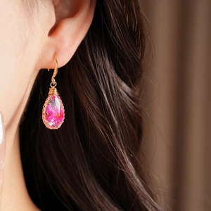Close-up detail of teardrop resin hook earrings with pink dried flowers and gold wire