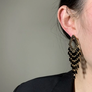 Close-up detail of elegant black and gold tassel drop earrings featuring sparkling zircon stones