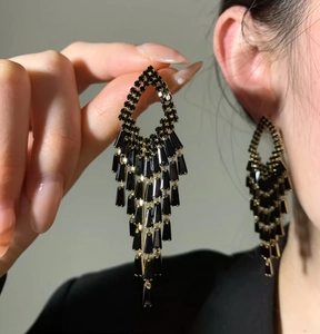 Detailed close-up view of elegant black tiered tassel earrings with shimmering gold settings