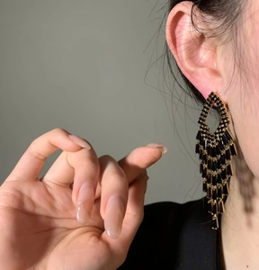 Dramatic close-up of luxurious black zircon tassel fringe earrings on model ear