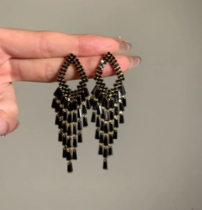 Close-up detail shot of elegant black rhinestone chandelier earrings held by hand