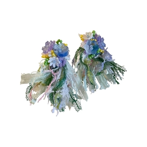 Orecchini a perno con fiori in resina fatti a mano e nappe di nastro colorato.