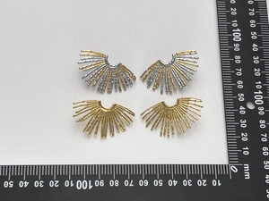 Macro detail of fan-shaped striped metal earrings with dimensions shown on a metric scale