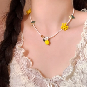 Detailed view of handmade beaded necklace with yellow flowers and lemon pendant