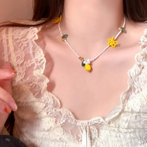 Macro detail showing a sweet beaded necklace with lemon and flower charms on a model
