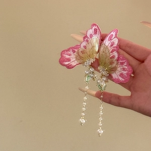 Gros plan sur des boucles d'oreilles papillon roses avec de longs pompons en perles