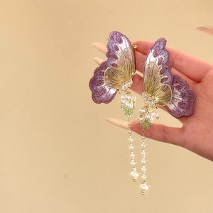 Vue détaillée des boucles d'oreilles papillon violettes avec glands de perles élégants
