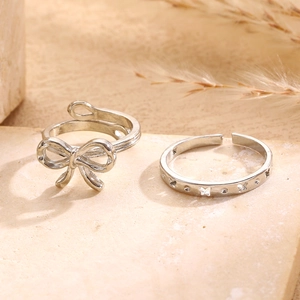 Detailed view of silver bow-knot and hollow butterfly rings on a stone surface