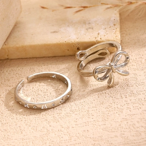 Detailed view of silver star and bow adjustable rings set on stone display base