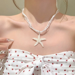 Close-up of a white resin starfish pendant necklace with a delicate organza cord.