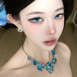Primo piano di una modella asiatica con collana di cristalli blu e orecchini a forma di sole