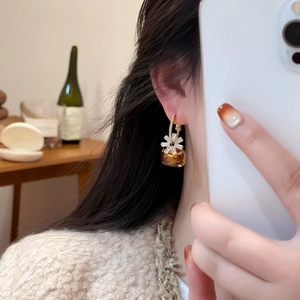 Close-up of sweet brown zircon flower drop earrings worn by a model in soft light
