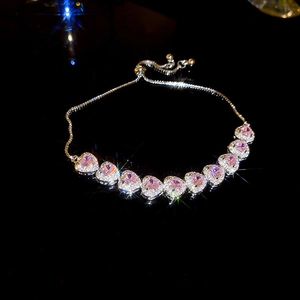 Vista detallada de una pulsera ajustable con brillantes piedras rosas en forma de corazón.