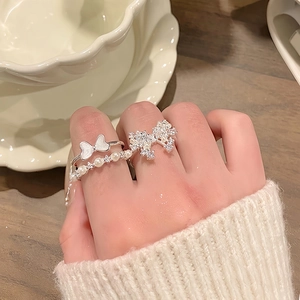 Close-up of three elegant silver rings featuring butterfly, pearl, and zircon details