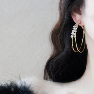 Detail view of gold double-layered hoop earrings with sparkling zircon accents.