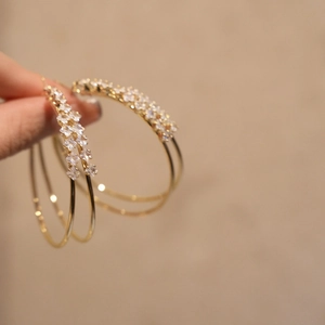 Close-up detail of gold double-layer hoop ear clips with sparkling zircons