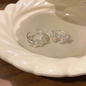 Detailed view of two silver rings with butterfly motifs, pearls, and zircons on a plate.