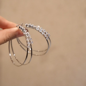 Detailed close-up of silver double-layered hoop earrings with sparkling cubic zirconia.