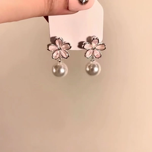 Close-up of elegant pink flower earrings with round pearl drops