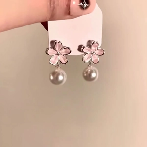 Close-up of elegant pink flower earrings with delicate pearl pendants