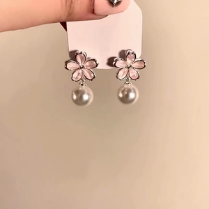 Macro detail of elegant pink flower stud earrings with lustrous white pearl drops