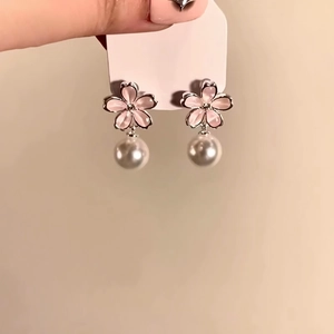 Detail view showing elegant pink flower stud earrings with hanging white pearl drops