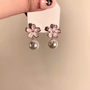 Close-up of elegant pink flower stud earrings with hanging white round pearls on tag.