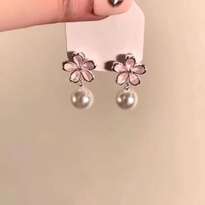 Detailed close-up view of feminine pink flower stud earrings with elegant white pearl drops.