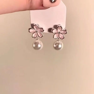 Close-up of pink flower earrings with pearl drops on a white card