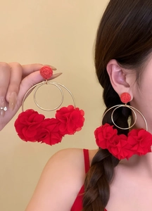 Detailed visual of oversized red fabric flower hoop earrings worn by an Asian model